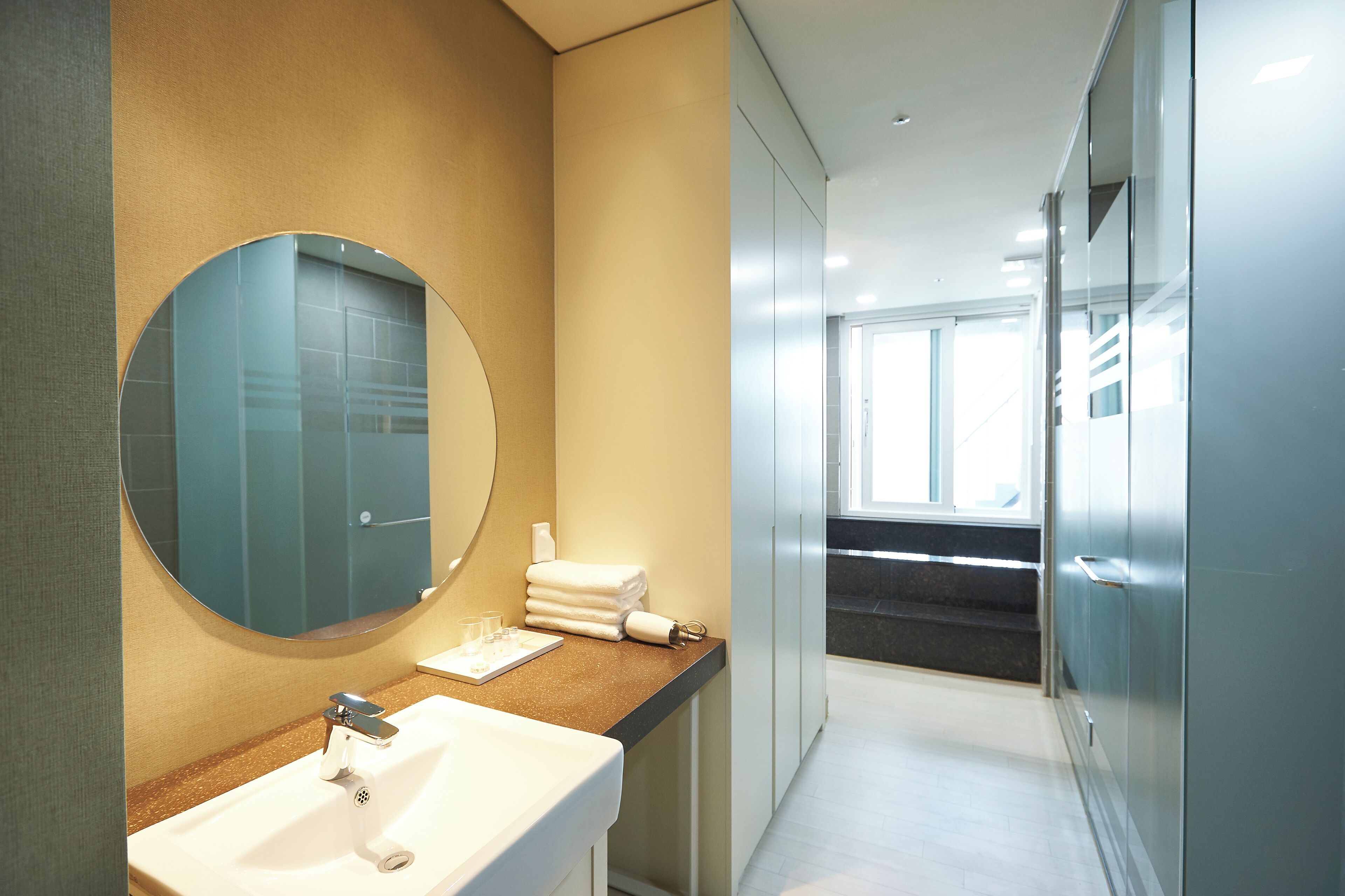 A modern bathroom with a round mirror, a sink, and a towel rack.