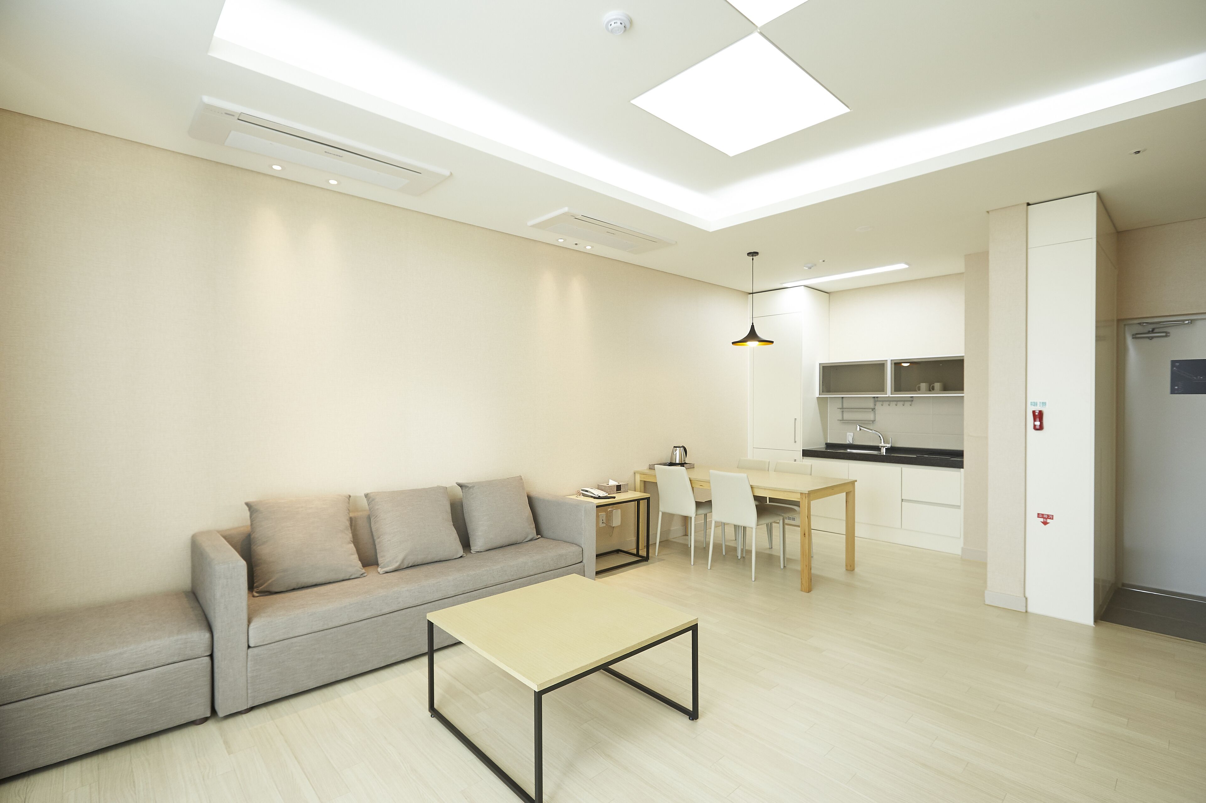 A modern living room with a sofa, a coffee table, and a dining area with chairs and a table.