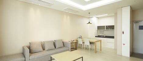 A modern living room with a sofa, a coffee table, and a dining area with chairs and a table.
