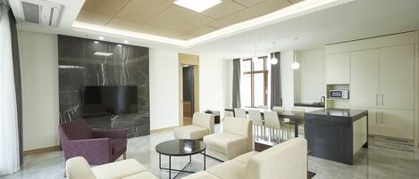 A modern living area with a sofa set, a coffee table, and a kitchen area with a microwave.