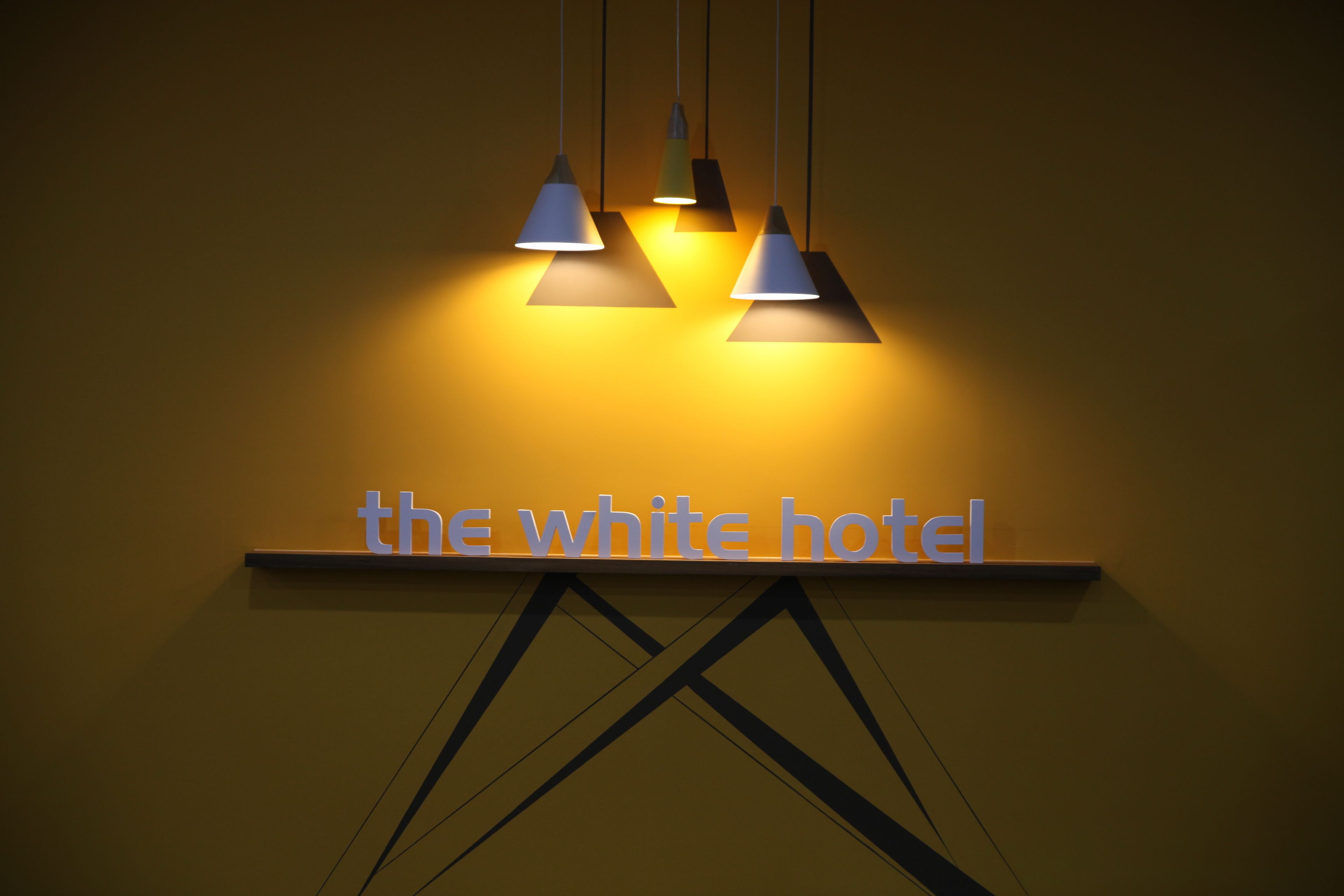 Letrero de 'The White Hotel' con tres lámparas colgantes.