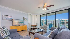 Ein modernes Wohnzimmer mit Sofa, Couchtisch, Fernseher und einem Balkon mit Blick.