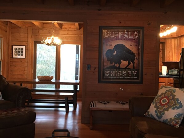 Un intérieur en bois agrémenté d’une affiche sur le thème des bisons et représentant du whisky, un coin repas avec un banc et un espace cuisine.