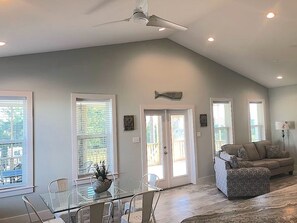 Relax in this spacious living area with a high ceiling, ceiling fan, and large window, perfect for taking in the view.