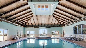 Una amplia piscina interior con techos altos y luz natural que entra por grandes ventanales.