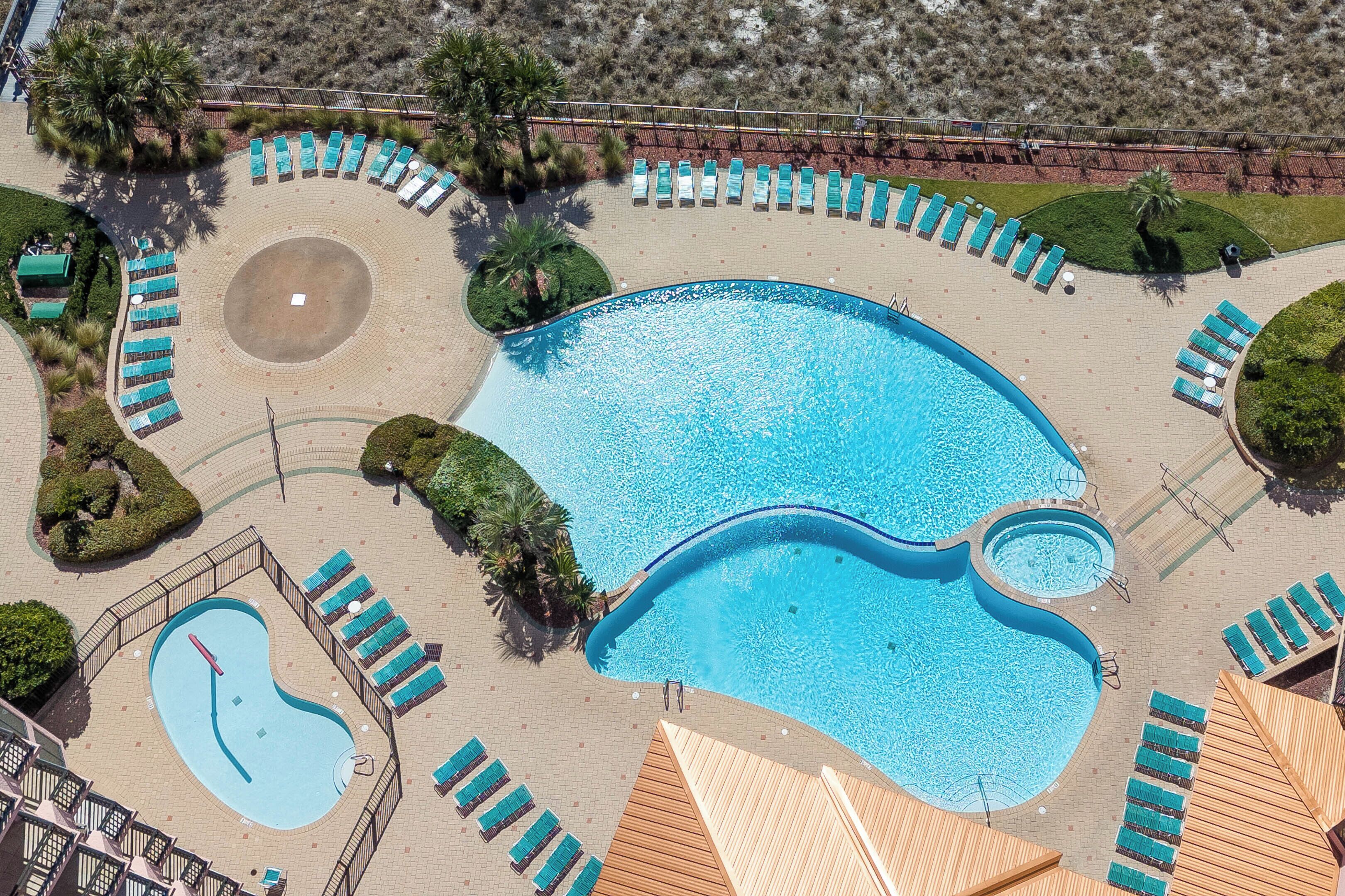 Ein großer Pool mit mehreren Liegestühlen und einem separaten, kleineren Poolbereich.