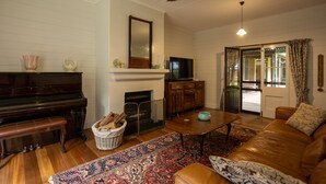 Una sala de estar con un piano, televisor, chimenea, sofá y ventilador de techo.