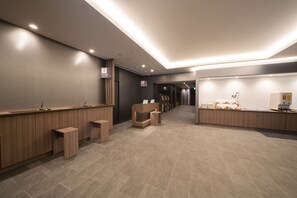 Una moderna zona de recepción con un mostrador de madera, un área de espera con sillas y un mostrador con una computadora y papeles.