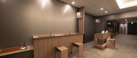 Un'area reception moderna con una scrivania in legno, un piccolo angolo salotto e una segnaletica indicativa della posizione.