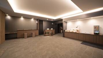 A modern reception area with a wooden reception desk, a waiting area with a bench, and a counter with a computer and a display.