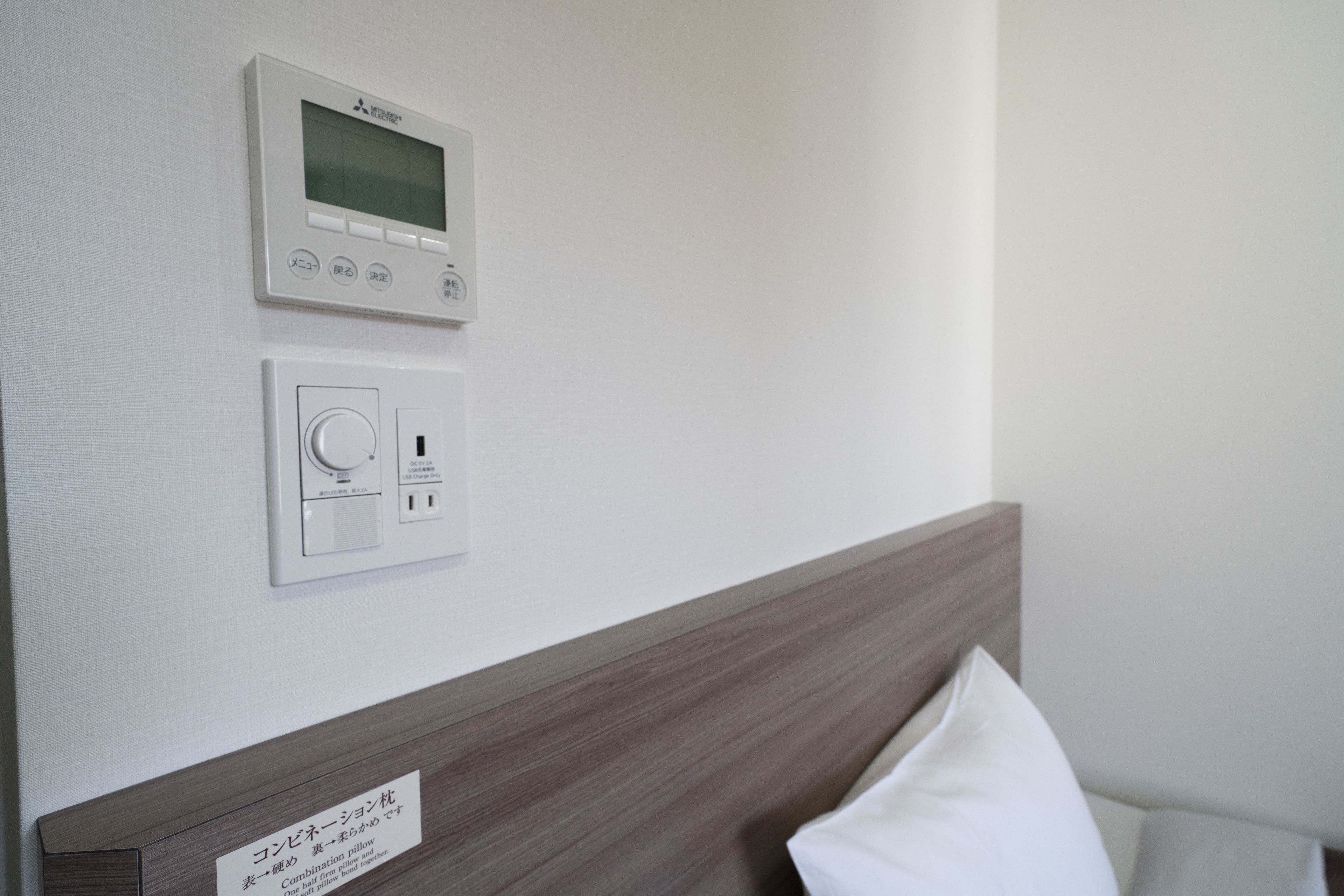 A wall-mounted thermostat and control panel in a hotel room.