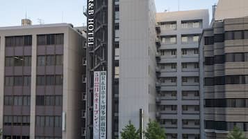A multi-story hotel with a prominent R&B Hotel sign, surrounded by other buildings and trees.