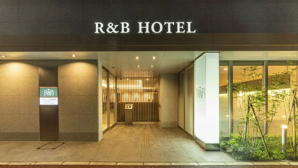 Das R&B Hotel von außen mit einem modernen Eingangsbereich, einer Rezeption und einem Schild mit dem Namen des Hotels.