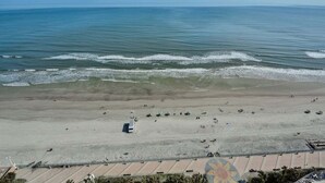 A beach with a parking lot and a bus. - Ocean Front Delight - Ocean Walk (Daytona Beach)