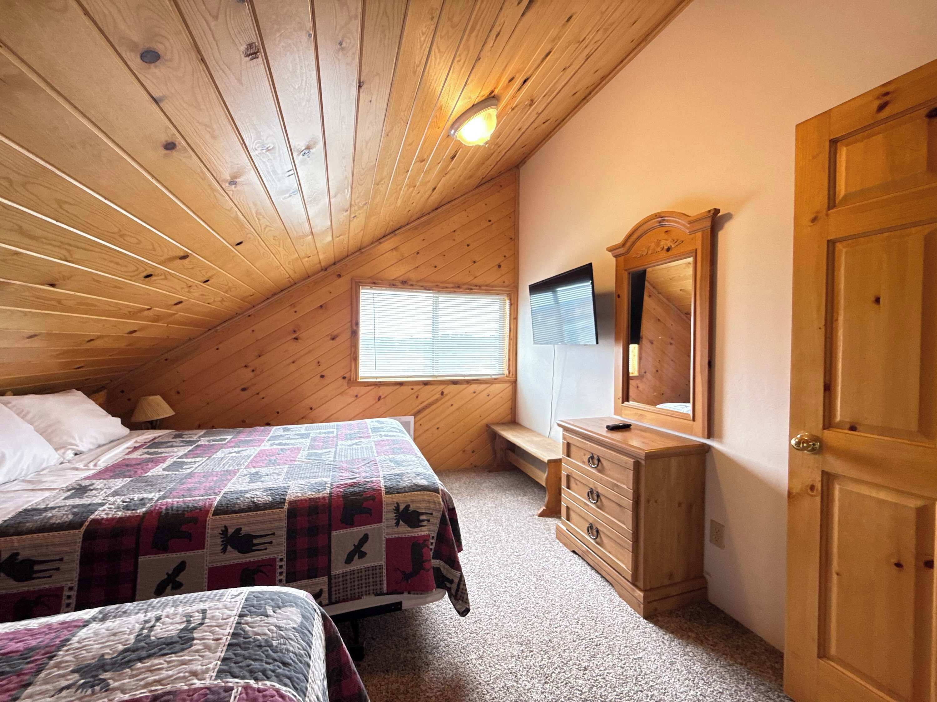 Une chambre avec deux lits, une commode, un miroir et une fenêtre.