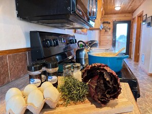 A kitchen with a stove, a blue pot on the counter, and various spices and eggs.