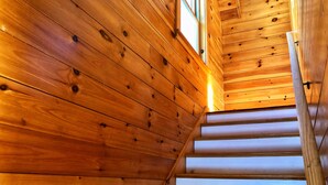 A wooden staircase with a handrail, leading upwards.