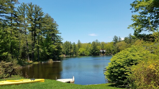 A lakeside view with a dock, a yellow kayak, and a cabin in the background. - Idyllic Lakefront House Suited Two  Families (Ludlow)