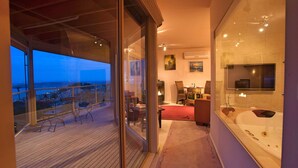 Un interior moderno con un balcón que da a una vista urbana al atardecer.