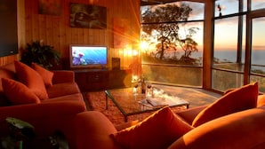 Una sala moderna con un televisor grande, sofás naranjas y una mesa de centro de vidrio.