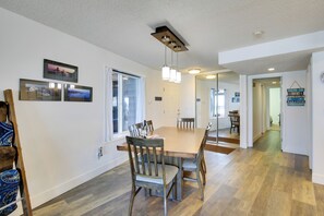 A dining area with a wooden table and chairs, a ceiling light fixture, and framed pictures on the wall. - Lincoln City Beach Condo: Clubhouse & Pool Access! (Lincoln City)