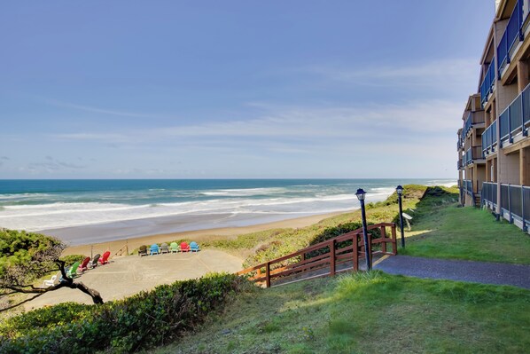A beach view from a hotel balcony with a sandy beach, ocean, and a staircase leading down to the beach. - Lincoln City Beach Condo: Clubhouse & Pool Access! (Lincoln City)