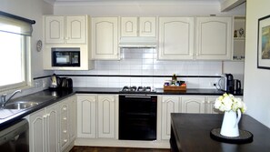 A kitchen with white cabinets, a microwave, a gas stove, and a dishwasher.
