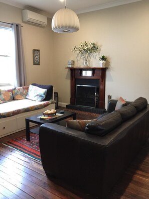 A living room with a sofa, a coffee table, a fireplace, and a hanging light fixture.
