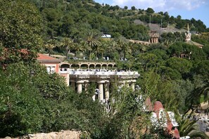 Un edificio histórico con arcos y columnas, rodeado de exuberante vegetación y colinas.