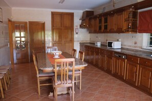 A kitchen with wooden cabinets, a granite countertop, and a dining area with a table and chairs. - HOME SOUSA tranquility for your holiday in family 10 minutes from the beach !! (Lagos)