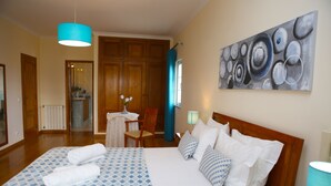 Een hotelkamer met een groot bed, een houten hoofdbord, een schilderij aan de muur en uitzicht op de badkamer door een open deur.