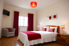 A bedroom with a bed, a nightstand, a chair, a window with curtains, a wall-mounted TV, and a ceiling light. - HOME SOUSA tranquility for your holiday in family 10 minutes from the beach !! (Lagos)