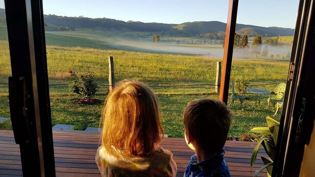A view from a room with a large window overlooking a grassy field and distant hills. - Hunter Valley Rural Lodge - Quaint towns, State forests & Wineries to explore! (Glendon Brook)