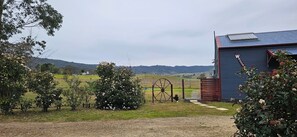 A rural landscape with a farm gate, a blue building, and rolling hills in the background. - Hunter Valley Rural Lodge - Quaint towns, State forests & Wineries to explore! (Glendon Brook)
