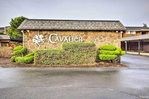 Welcome to Cavalier, a traditional building with a pitched roof and stone facade, set amidst well-mainters hedges and a paved entrance.