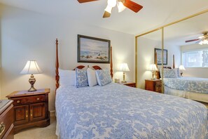 A bedroom with a large bed, two bedside tables, a nightstand, a ceiling fan, and a mirror. - Cozy Oregon Resort Condo - Steps to Lincoln Beach! (Lincoln City)