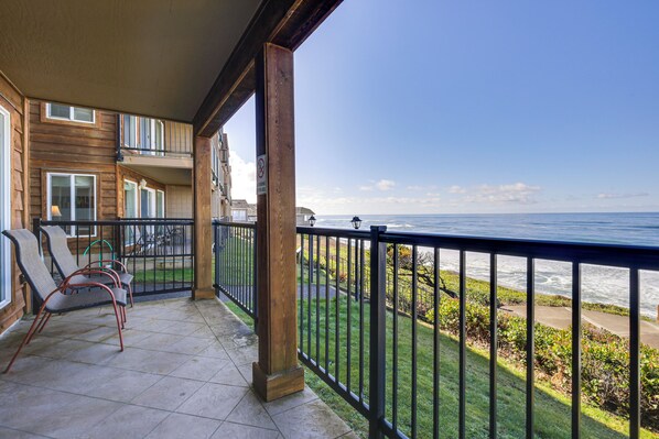 A balcony with a view of the ocean, wooden railings, and outdoor furniture. - Cozy Oregon Resort Condo - Steps to Lincoln Beach! (Lincoln City)
