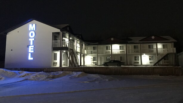 A motel with a prominent 'MOTEL' sign, multiple balconies, and a car parked in front. - Langham Motel (Langham)