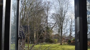 A view through a window of a grassy yard with a stone pathway and trees. - ★Walnut Tree Cottage★ Huge garden+village setting+near Canterbury+dog friendly (Canterbury)