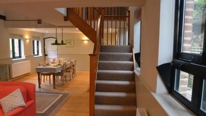 A staircase leading to a loft bedroom, a dining area with a table and chairs, and a red sofa in a well-lit room with large windows. - ★Walnut Tree Cottage★ Huge garden+village setting+near Canterbury+dog friendly (Canterbury)