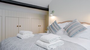 A neatly made bed with folded towels, a bedside lamp, and striped pillows. - ★Walnut Tree Cottage★ Huge garden+village setting+near Canterbury+dog friendly (Canterbury)