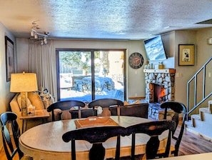 Un coin repas chaleureux avec une table ronde, des chaises, une lampe et une cheminée.