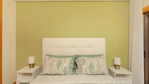 A bedroom with a white headboard, two bedside tables with lamps, and a bed with patterned pillows. - Beach and City Getaway (Vila Nova de Gaia)