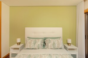 A bedroom with a white headboard, two bedside tables with lamps, and a bed with patterned pillows. - Beach and City Getaway (Vila Nova de Gaia)