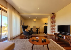 Un salon moderne comprenant un canapé, une table basse ronde, un téléviseur et un coin repas avec des chaises et une table.