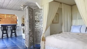 A bedroom with a canopy bed, a decorative partition, and a dining area with chairs and a table. - Crew's Nest at Bayview Villas, Poolside Studio close to Grafton Beach (Black Rock, Pleasant Prospect)