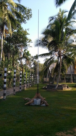 Surrounded by lush greenery and palm trees, this serene outdoor space features a striking central pole.