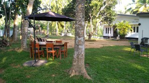 Enjoy a tranquil outdoor dining experience surrounded by lush greenery and a picturesque porch.
