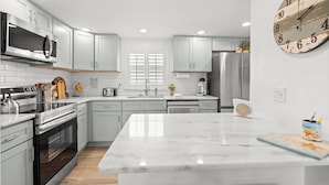 A modern kitchen with white cabinets, stainless steel appliances, and a large island. - Island House Beach Resort V5 (Siesta Key)