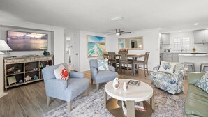 A spacious living room with a large TV, comfortable seating, a dining area, and a kitchen. - Island House Beach Resort V5 (Siesta Key)